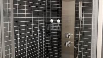 Een bad/douchecombinatie, een bubbelbad, een haardroger, handdoeken