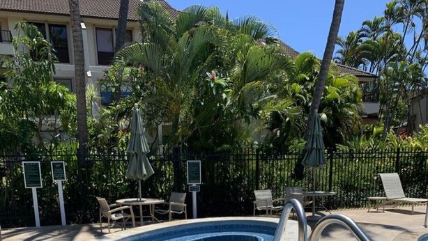 A swimming pool with a tiled edge, surrounded by lounge chairs and palm trees. - An Affordable Alternative to Expensive Accommodations in Poipu (Poipu)