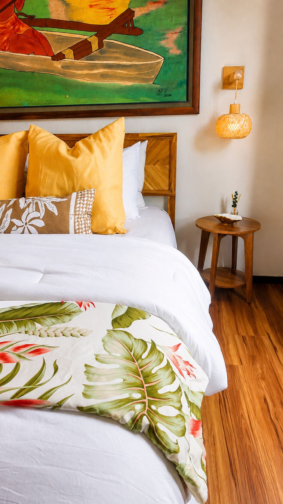 A neatly made bed with a floral comforter, a wooden headboard, and a small wooden nightstand with a lamp.