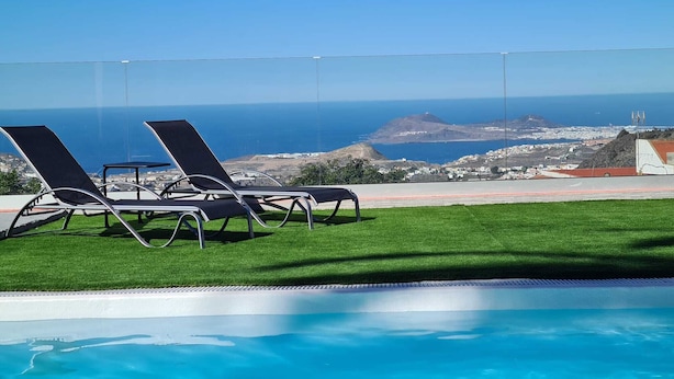 A pool area with two lounge chairs and a view of the ocean. - Happy Family Villa (Arucas)