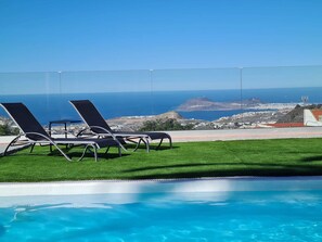 A pool area with two lounge chairs and a view of the ocean. - Happy Family Villa (Arucas)