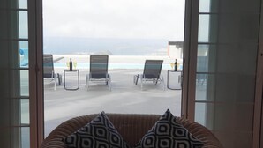 A room with a view of the beach, featuring two lounge chairs and a table with drinks. - Happy Family Villa (Arucas)