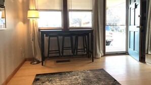 Ett rum med ett träbord och två stolar, en lampa och en dörr som leder ut.