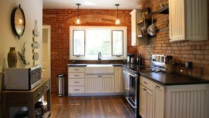 A kitchen with a brick wall, white cabinetry, a double sink, and pendant lighting. - Historic Neighborhood 2 Blocks from Downtown Bozeman. (Bozeman)