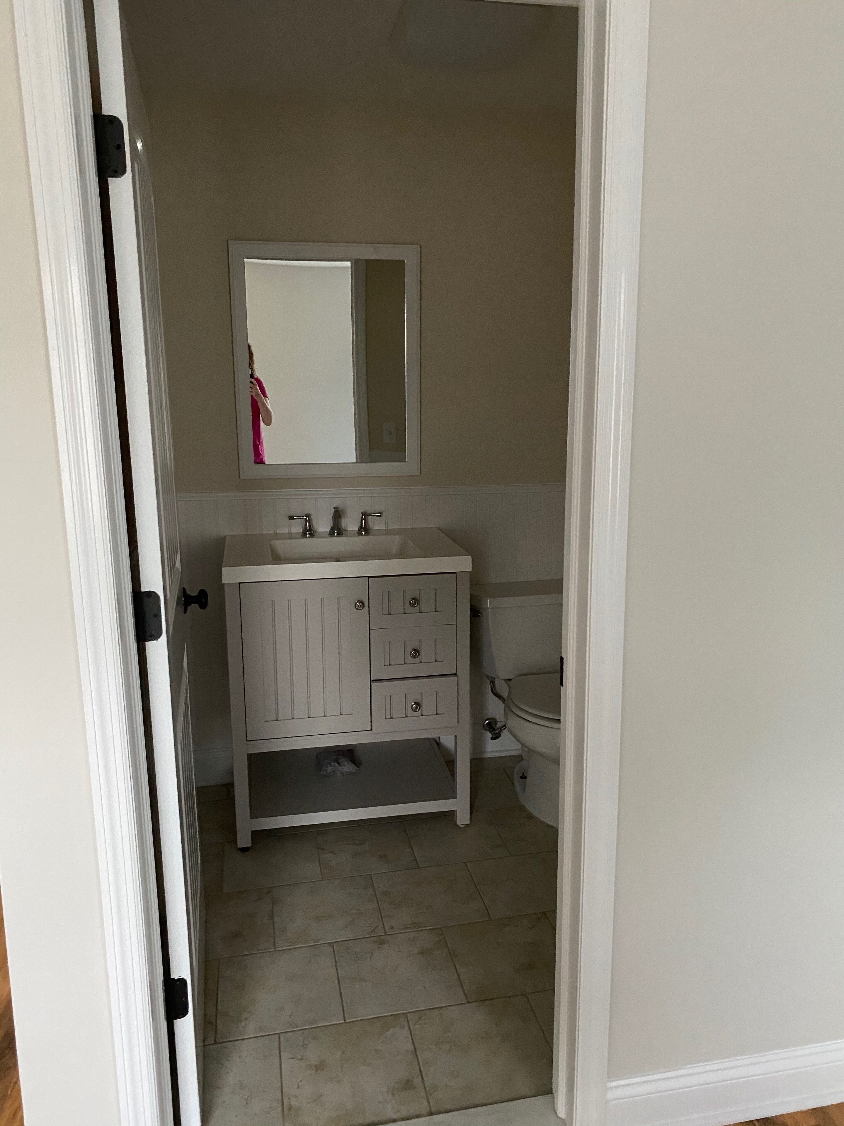 Une salle de bain avec un meuble-lavabo blanc, un miroir et des toilettes.