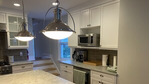 A modern kitchen with white cabinets, a marble countertop, a built-in microwave, and pendant lighting. - Beautiful, family friendly Bradley Beach home 1.5 blocks from the beach! (Bradley Beach)