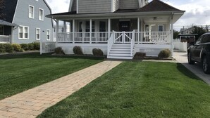 A two-story house with a covered porch and a brick pathway leading to the front door. - Beautiful, family friendly Bradley Beach home 1.5 blocks from the beach! (Bradley Beach)