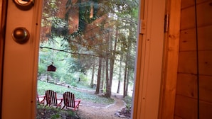 A wooden door leading to a forested area with a bench and a birdhouse. - Waterfall Cottage within sight & sound of Cane Creek Falls, 2BR 2BA (Dahlonega)