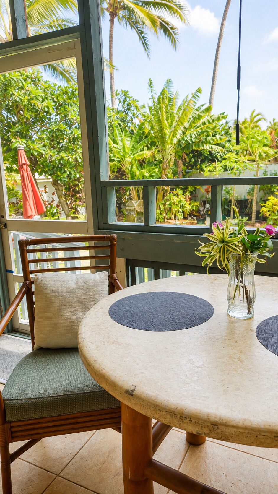 A round table with a cushion, a chair with a cushion, and a vase with plants.