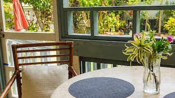 A round table with a cushion, a chair with a cushion, and a vase with plants.