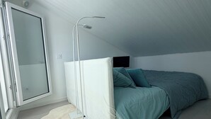 A bedroom with a bed, a white radiator, a fluffy rug, and a window. - MAISON LITTLE WHITE HOUSE (Anglet)
