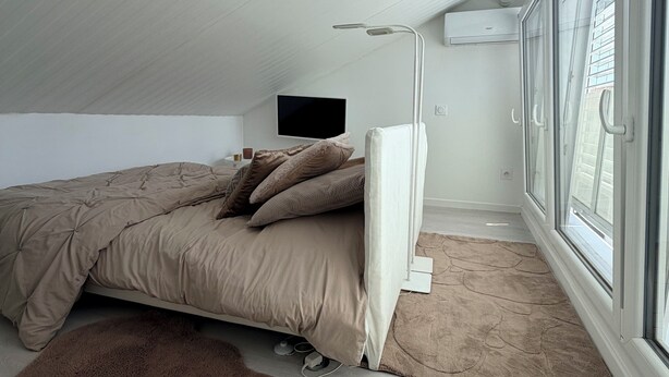 A bedroom with a bed, a TV, a window, and a ceiling fan. - MAISON LITTLE WHITE HOUSE (Anglet)