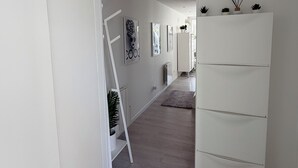 A hallway with a white refrigerator, a white cabinet, and a white shelf with decorative items. - MAISON LITTLE WHITE HOUSE (Anglet)