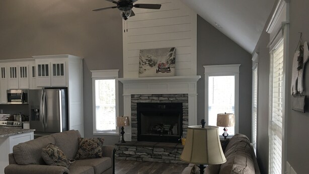 Un salon avec une cheminée, deux canapés, une table basse et un ventilateur de plafond.