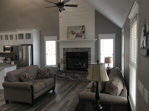 A living room with a fireplace, two sofas, a coffee table, and a ceiling fan. - Family Friendly Guest house-3 bedroom, 2 bath. Custom farm/craftsman (Mountain View)