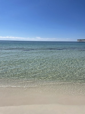 A beach with clear water and a pier in the distance. - Waterfront Home with Boat Dock and kayaks! (Milton)