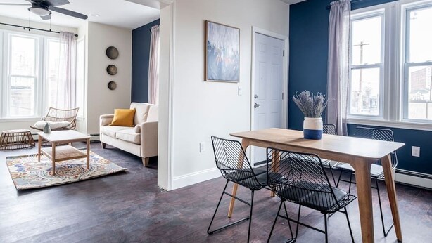 Una sala de estar moderna con una mesa de comedor, sillas, un sofá y un ventilador de techo.