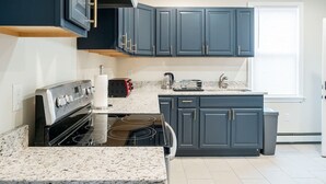 Una cocina moderna con armarios azul oscuro, una estufa negra y una encimera de granito.