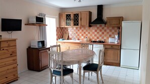 A compact kitchen with wooden cabinets, a microwave, a stove, and a refrigerator. - 10 minutes walk from the waterfall, bright apartment, pets welcome! (Saint-Laurent-le-Minier)