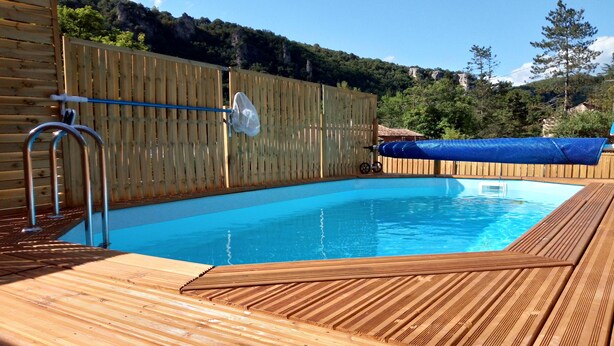 A wooden deck surrounding a rectangular swimming pool with a wooden fence and a satellite dish. - 10 minutes walk from the waterfall, bright apartment, pets welcome! (Saint-Laurent-le-Minier)