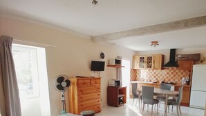 A compact living space with a dining area, kitchenette, and a small table with a chair. - 10 minutes walk from the waterfall, bright apartment, pets welcome! (Saint-Laurent-le-Minier)