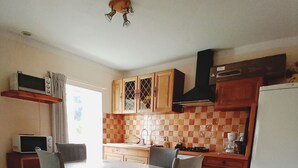 A kitchen with a dining table, chairs, cabinets, a microwave, and a refrigerator. - 10 minutes walk from the waterfall, bright apartment, pets welcome! (Saint-Laurent-le-Minier)