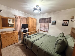 A bedroom with a bed, a dresser, a television, a wardrobe, a window with blinds, and a ceiling light fixture. - 0.6 miles to Downtown, 3.9 miles to RMNP, Hot Tub, Activity Shed! Far View Cabin (Estes Park)