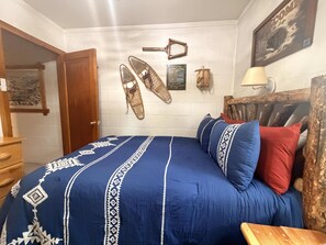 A bedroom with a bed, a wooden headboard, a wall-mounted lamp, and a door. - 0.6 miles to Downtown, 3.9 miles to RMNP, Hot Tub, Activity Shed! Far View Cabin (Estes Park)