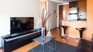 A modern living room with a flat-screen TV, a coffee table, and a vase with decorative branches. - Apoquindo Green (Santiago)