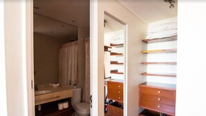 A bathroom with a toilet, sink, and wooden storage unit with shelves and drawers. - Apoquindo Green (Santiago)