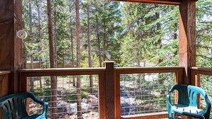 A wooden deck with a metal railing, two green plastic chairs, and a view of a forested area. - Unbeatable Location; Walk to Lift/Town/Trails; Heated Boot Dryer (Breckenridge)