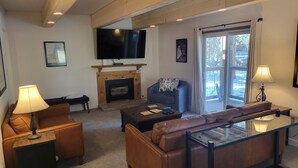 A living room with a fireplace, leather sofas, a glass coffee table, and a television mounted on the wall. - Unbeatable Location; Walk to Lift/Town/Trails; Heated Boot Dryer (Breckenridge)