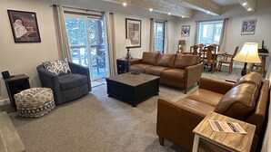 A spacious living room with a wooden ceiling, a large sofa, a coffee table, and a dining area with wooden chairs and a table. - Unbeatable Location; Walk to Lift/Town/Trails; Heated Boot Dryer (Breckenridge)
