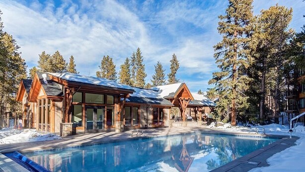 A pool area with wooden cabins, surrounded by snow and trees. - Unbeatable Location; Walk to Lift/Town/Trails; Heated Boot Dryer (Breckenridge)