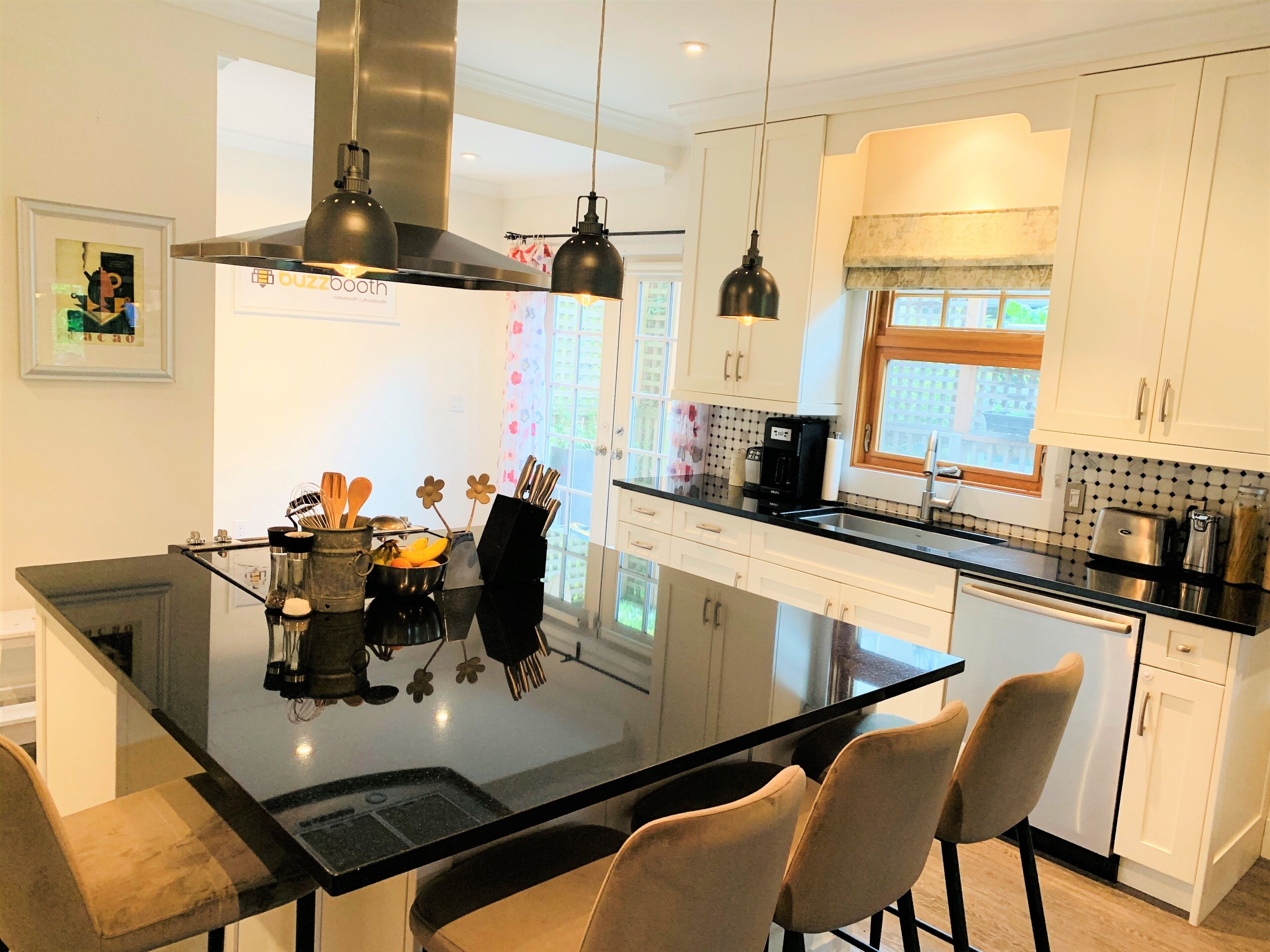 Een moderne keuken met een centraal eiland, witte kasten en een zwart aanrecht.