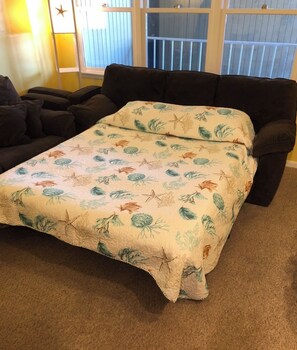 Relax in this inviting living room with a comfortable sofa, throw blanket, and natural light.