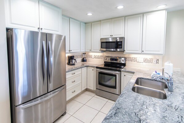A modern kitchen with stainless steel appliances, white cabinets, and a granite countertop. - Gulf Front, 3 Bedroom Condo, Small Complex, Dune Allen Beach, Santa Rosa Beach (Santa Rosa Beach)