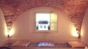 A room with a sloped ceiling, a small window, and a bed with a headboard.