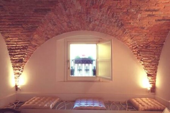 A room with a sloped ceiling, a small window, and a bed with a headboard.