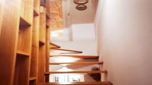 A wooden staircase with a modern design, leading to a room with a white wall and a framed picture.