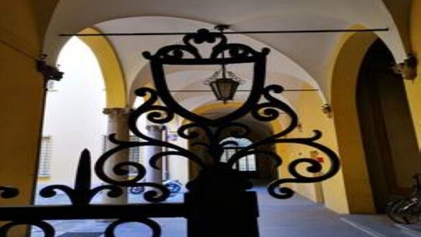 An arched corridor with a decorative iron gate and a bicycle parked outside.