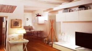 A modern living room with a flat-screen TV, a small table with a lamp, and a sofa.