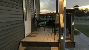 En træterrasse med udendørs møbler, et lille bord og en lygte.
