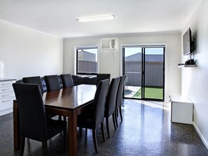 Enjoy meals at the dining table surrounded by comfortable seating, with a sliding door leading to an outdoor space.