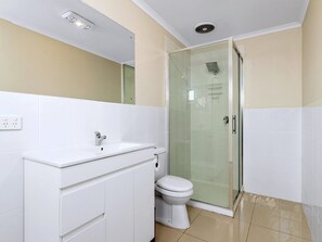 Bathroom features a vanity, toilet, and glass-enclosed shower area.