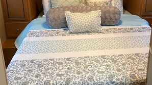 Ein Schlafzimmer mit einem Bett, mehreren Kissen und Holzschränken darüber.