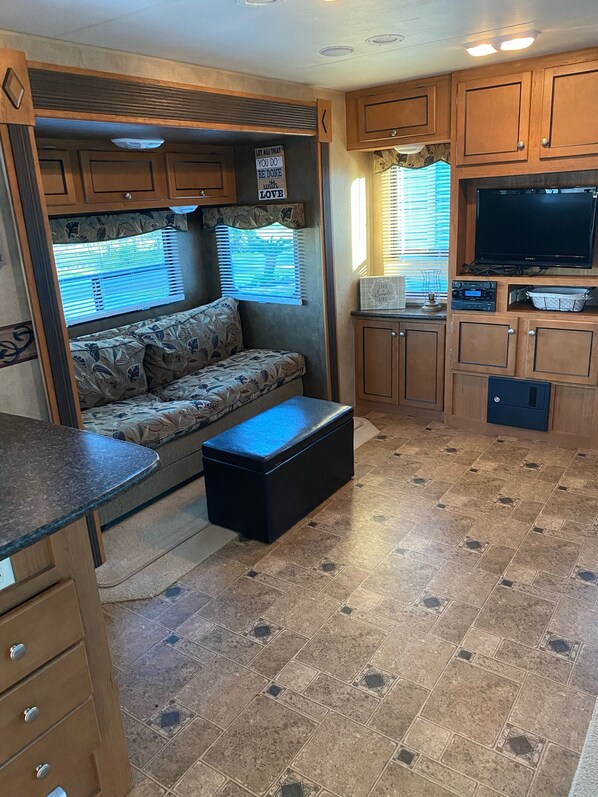 A compact RV interior with a kitchenette, a sofa, and a television. - RV 1 of 2 on Canal and 1/2 mi from Beach (Private Lot) (Crystal Beach)