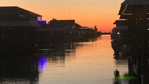 Ruhige Wasserfläche mit Gebäuden an beiden Ufern, die den Sonnenuntergang spiegeln.