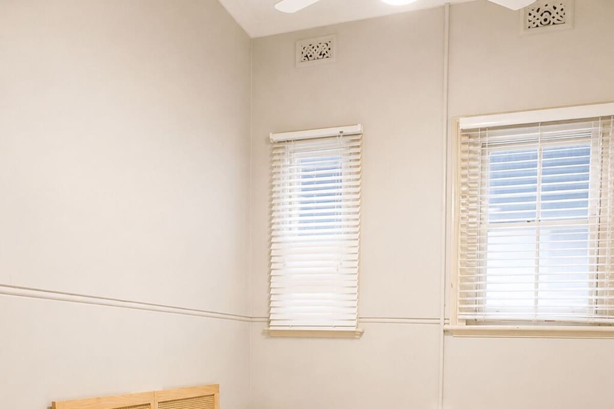 A neatly arranged bedroom with a bed, bedside tables, and a round rug.