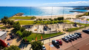 A coastal area with a parking lot, a circular plaza with seating, and a view of the sea.